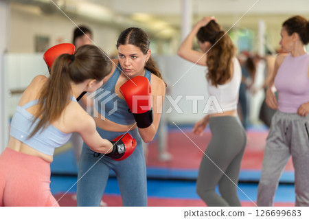 Women in boxing gloves practice boxing techniques Women in boxing gloves practice boxing techniques 126699683