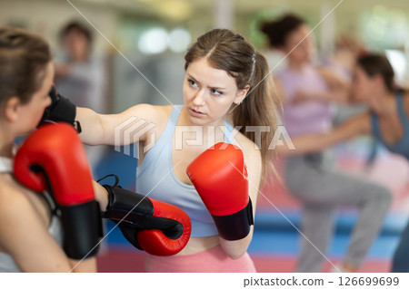 Woman with boxing gloves learning punches Woman with boxing gloves learning punches 126699699
