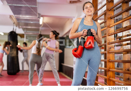 Woman athlete with boxing gloves pose before training in gym Woman athlete with boxing gloves pose before training in gym 126699756