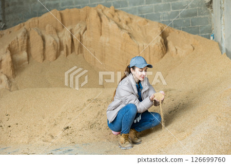 Woman farmer holding handful of soybean husk, in animal food storage 126699760