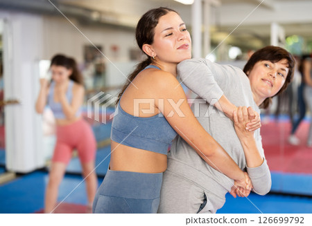 Women in pair perform effective impact on pain points while learning self-defense. 126699792