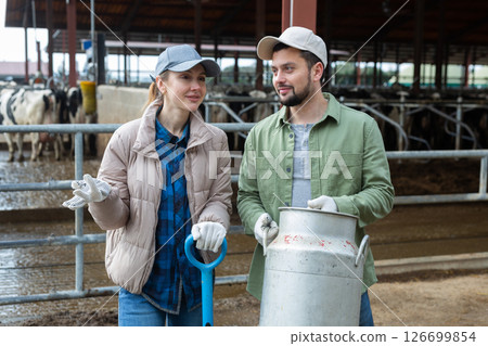 Farmer couple standing with milk churn at livestock farm and talking 126699854