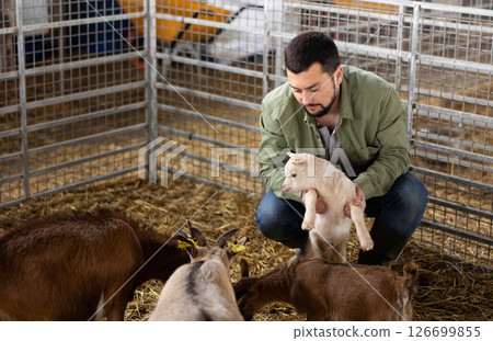 Positive male farmer taking care of goatlings 126699855