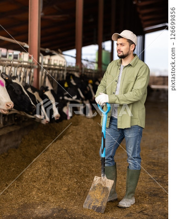 Farmer with shovel standing in cowshed 126699856