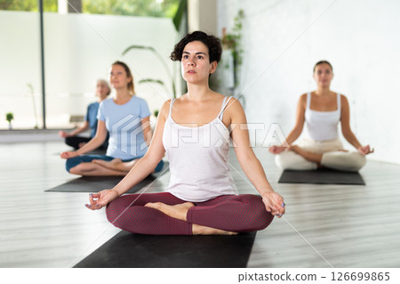 Portrait of latin american woman making yoga meditation in lotus pose in fitness studio Portrait of latin american woman making yoga meditation in lotus pose in fitness studio 126699865