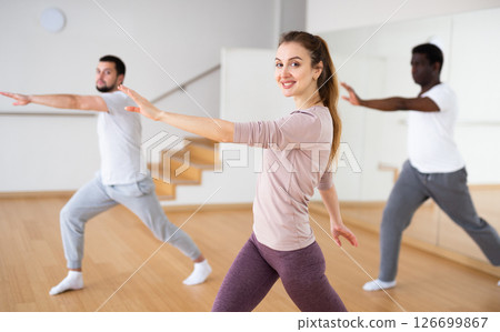 Young woman practicing vigorous dance movements with group Young woman practicing vigorous dance movements with group 126699867