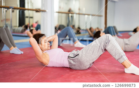Group exercise in gym - women doing abdominal exercises Group exercise in gym - women doing abdominal exercises 126699873
