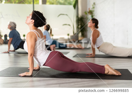 Group of women practicing yoga training - pose bhujangasana Group of women practicing yoga training - pose bhujangasana 126699885