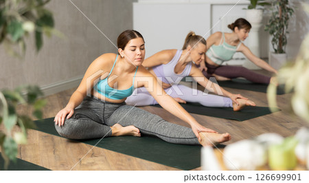 Young woman doing stretching asana Janu Sirsasana 126699901