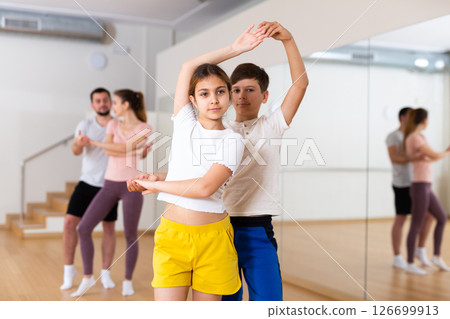Girl and boy dancing waltz together during rehearsal in dancing room Girl and boy dancing waltz together during rehearsal in dancing room 126699913
