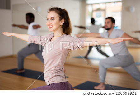 Woman practising warrior II pose in gym Woman practising warrior II pose in gym 126699921