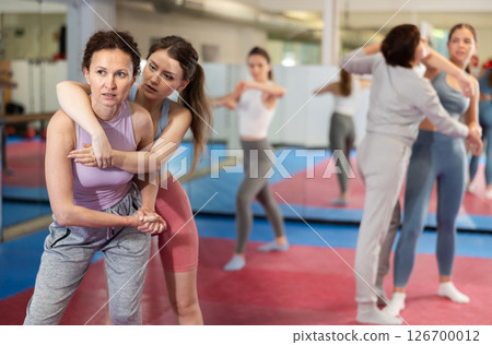 Women in pair perform effective impact on pain points while learning self-defense. Women in pair perform effective impact on pain points while learning self-defense. 126700012