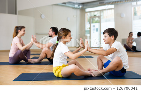 Teen boy and girl practicing partner yoga during family training Teen boy and girl practicing partner yoga during family training 126700041