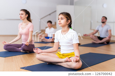 Young girl sitting in lotus pose with mother in gym Young girl sitting in lotus pose with mother in gym 126700042