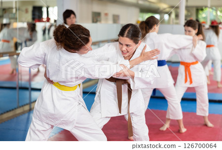 Women in self-defense training in white kimono with belts Women in self-defense training in white kimono with belts 126700064