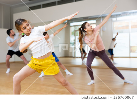 Girl practising dance moves with parents and sibling indoors Girl practising dance moves with parents and sibling indoors 126700067