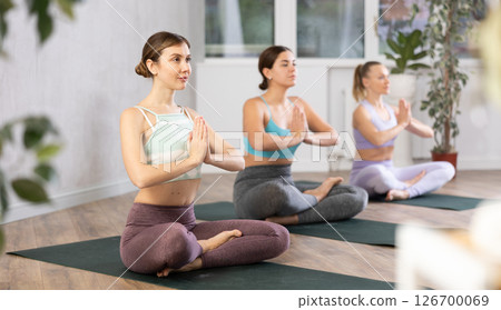 Sport women perform the exercise while sitting in the lotus position Sport women perform the exercise while sitting in the lotus position 126700069