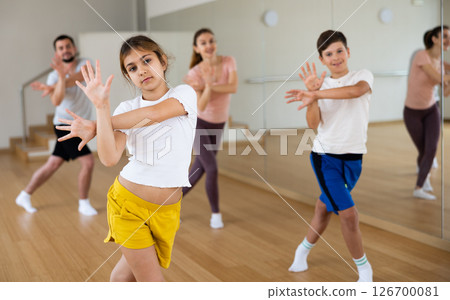 Smiling teenage girl enjoying active dance with family in studio 126700081