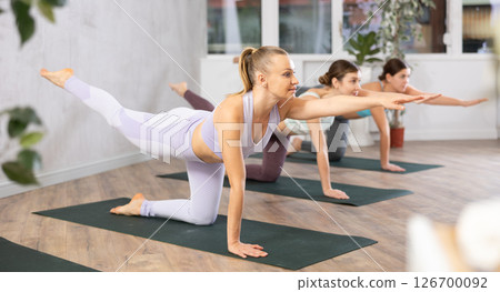 Group of active women practice various yoga poses Group of active women practice various yoga poses 126700092