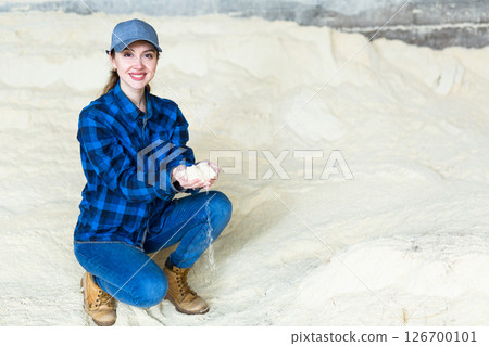 Woman checks the quality of cornmeal in an animal feed warehouse 126700101