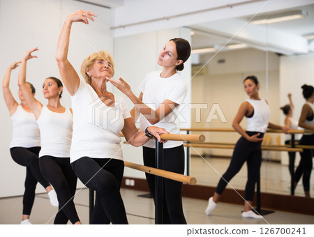 Various aged women exercising ballet moves with trainer Various aged women exercising ballet moves with trainer 126700241