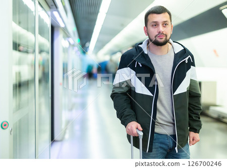 Young man standing with suitcase on subway station platform Young man standing with suitcase on subway station platform 126700246