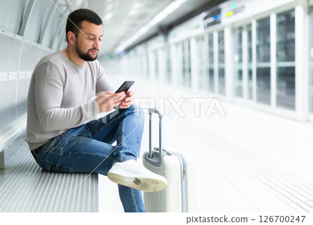 Male passenger in clothing reading his mobile phone in subway Male passenger in clothing reading his mobile phone in subway 126700247