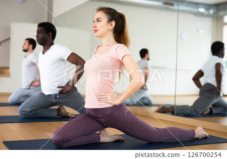 Woman with group doing stretching workout in yoga studio Woman with group doing stretching workout in yoga studio 126700254