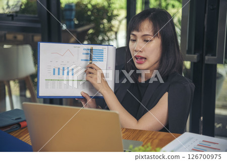 Business woman using smartphone, laptop on office desk. Female freelance reading financial graph charts Planning analyzing marketing data. Hands of young woman working in office firm business info. 126700975