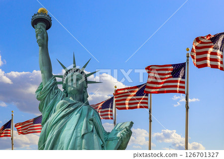 Statue of Liberty rises majestically with American flags fluttering in breeze on Ney York US 126701327