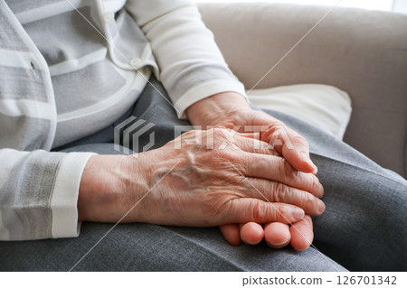 一位老婦人的手放在她的腿上 一位老婦人的手放在她的腿上 126701342