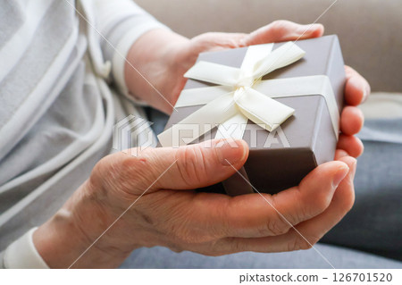 Senior woman's hands holding a gift Senior woman's hands holding a gift 126701520