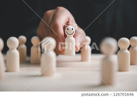 Hand picking a standout wooden figure for business hiring and recruitment. The chosen leader ensures success through teamwork and effective HR management. Hand picking a standout wooden figure for business hiring and recruitment. The chosen leader ensures success through teamwork and effective HR management. 126701646