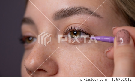 Young Woman Applying Mascara to Enhance Eyelashes. Young Woman Applying Mascara to Enhance Eyelashes. 126702012
