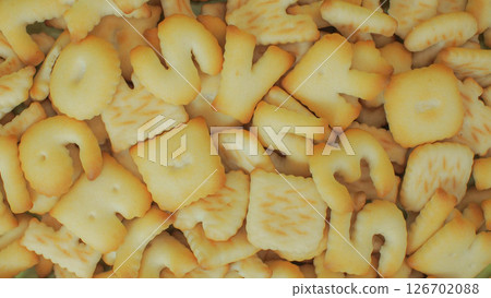 close-up image shows a pile of alphabet-shaped butter cookies, toasted to a light golden brown 126702088