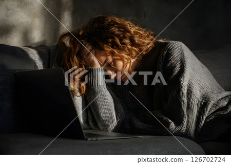 Young Caucasian woman sitting on a sofa looking tired 126702724