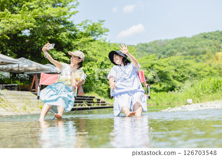 Camping: Woman dipping her feet in the river 126703548