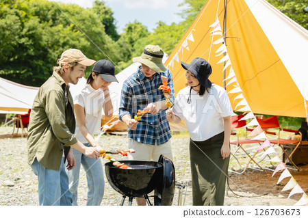 Men and women enjoying a barbecue at camp Men and women enjoying a barbecue at camp 126703673