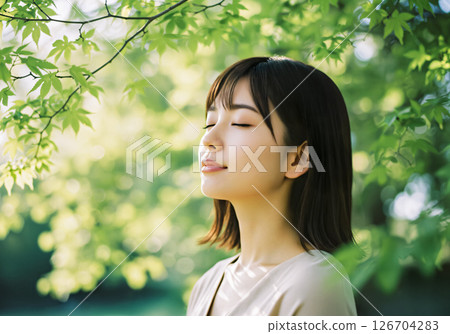 A woman feeling the power of nature with her eyes closed in the greenery A woman feeling the power of nature with her eyes closed in the greenery 126704283