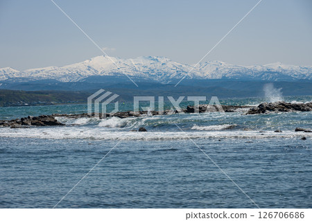 Waves splashing against Cape Kogane with the snow-capped Mashike Mountains in the background. 126706686