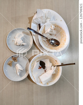 finished meal with empty bowls and crumpled napkins at restaurant table after dining experience. finished meal with empty bowls and crumpled napkins at restaurant table after dining experience. 126706921