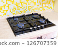 Close-up of a four-burner gas stove in a home kitchen. Bright blue flames 126707359
