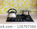 A kettle and a saucepan stand on a gas stove in a home kitchen 126707360
