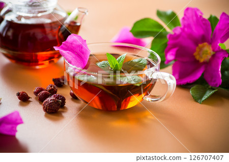 Aesthetic serving of tea with rosehip, petals and mint greens on brown background Aesthetic serving of tea with rosehip, petals and mint greens on brown background 126707407