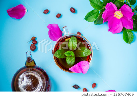 Aromatic natural drink with rosehip petals and a sprig of mint on blue background Aromatic natural drink with rosehip petals and a sprig of mint on blue background 126707409