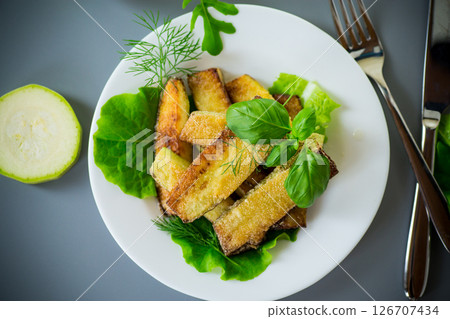 Fried zucchini slices with salad greens on a gray background 126707434