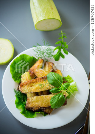 Homemade fried zucchini on a white plate on a gray background 126707435