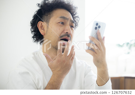 一名男子低頭看智慧型手機 126707632