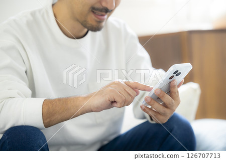 留著鬍鬚的男人在沙發上使用智慧型手機 126707713