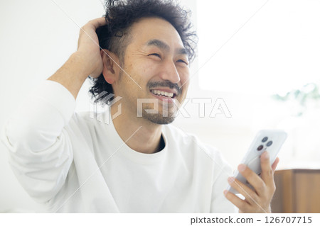 Bearded man using smartphone on sofa Bearded man using smartphone on sofa 126707715